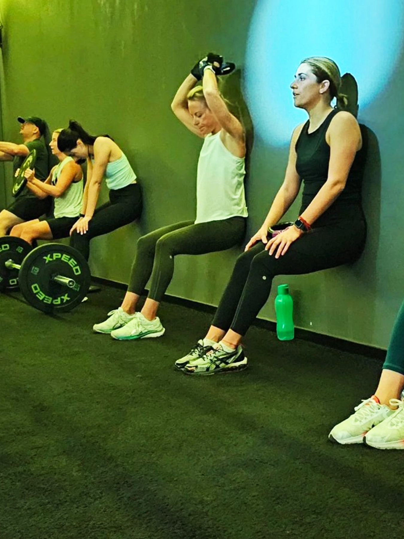 women doing wall sits at the gym
